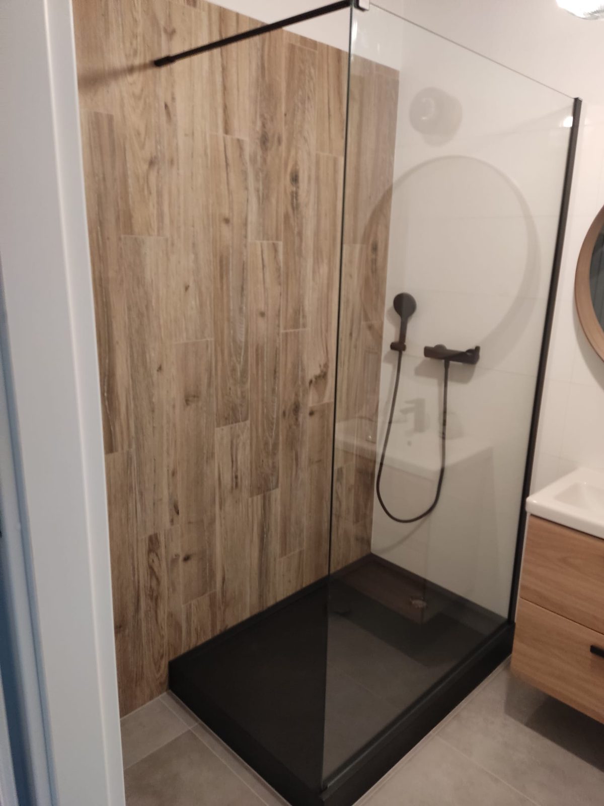Remont łazienki Warszawa – prysznic walk-in z czarnym brodzikiem i płytkami drewnopodobnymi