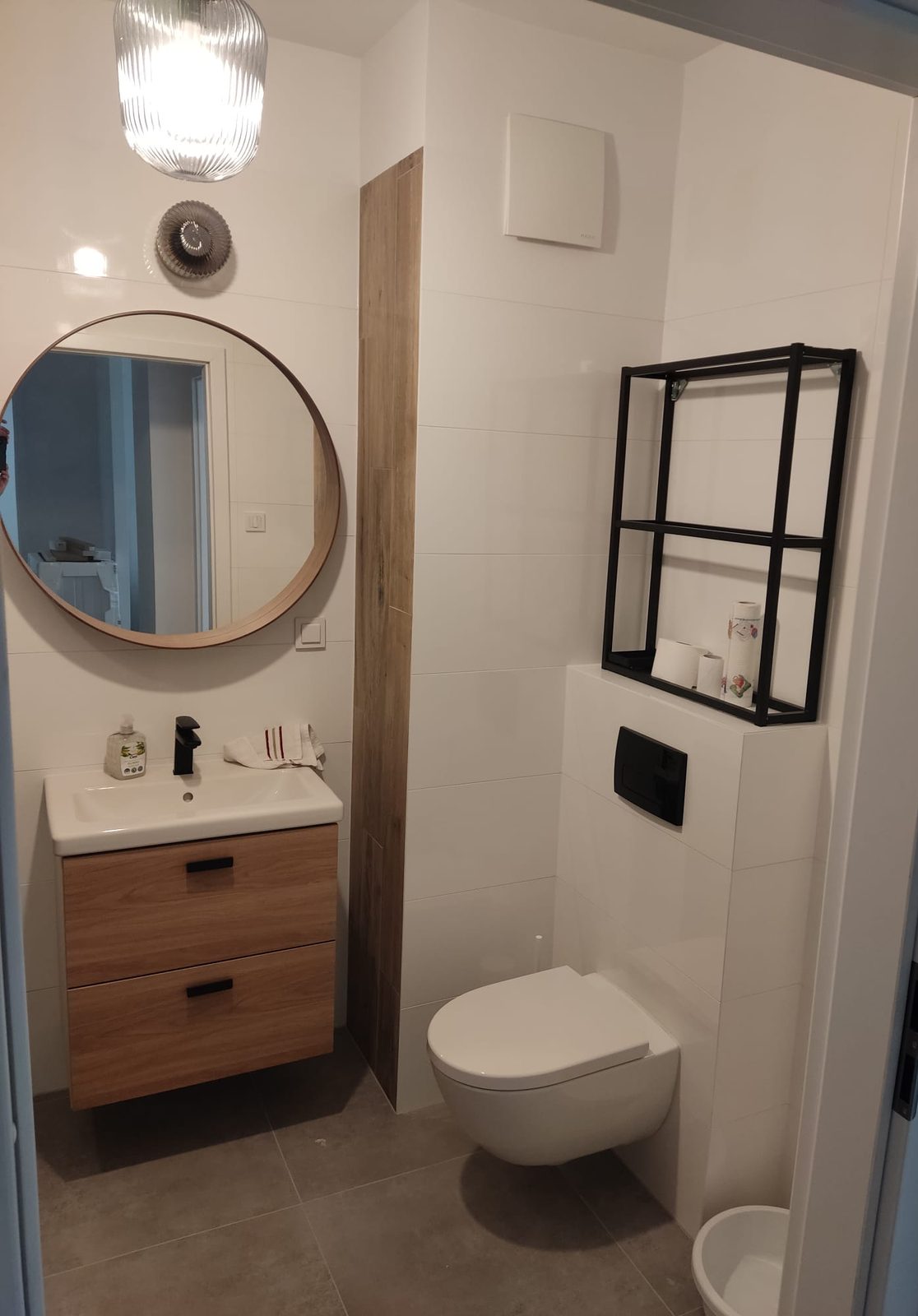 Wyremontowana łazienka w mieszkaniu – toaleta podwieszana, umywalka z szafką, okrągłe lustro